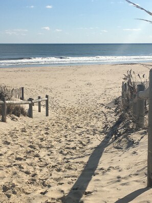 A sandy beach with a wooden fence and a wooden structure on the right. - Enjoy beautiful ocean views. Just park your car and have a very relaxing stay. (Harvey Cedars)