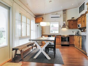 A modern kitchen with wooden cabinets, a dining table, and a bench. - Kotiranta by Interhome (Muhos)