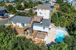 A two-story house with a backyard deck, a swimming pool, and a satellite dish.