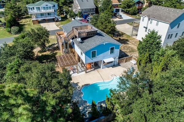 A residential property with a swimming pool, a deck, and a two-story house.