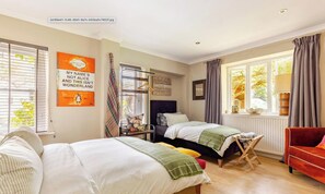 Ein Schlafzimmer mit zwei Betten, einem roten Sofa, einem Fenster mit Vorhängen und einem Poster an der Wand.