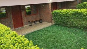 A two-story house with a red-tiled roof, a brick exterior, and a small front porch with a bench. - Manja Lodge (Zomba)
