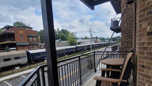 Un balcon donnant sur une gare et un bâtiment en briques.