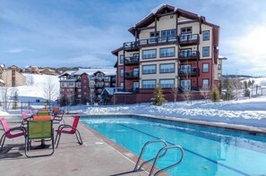 Relax by the rectangular pool surrounded by lounge chairs and a table.