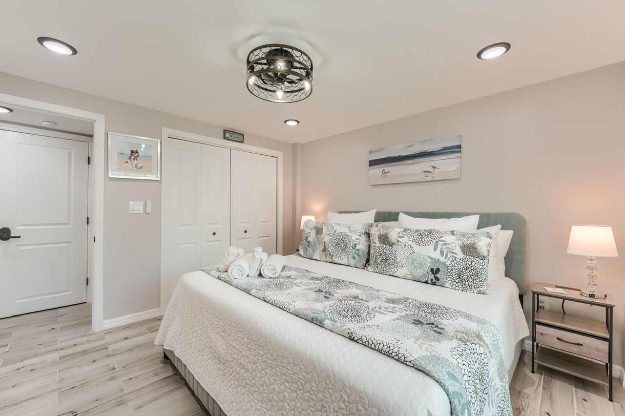 A bedroom with a bed, bedside table, and a ceiling light fixture.