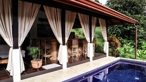 A covered outdoor seating area with a pool.