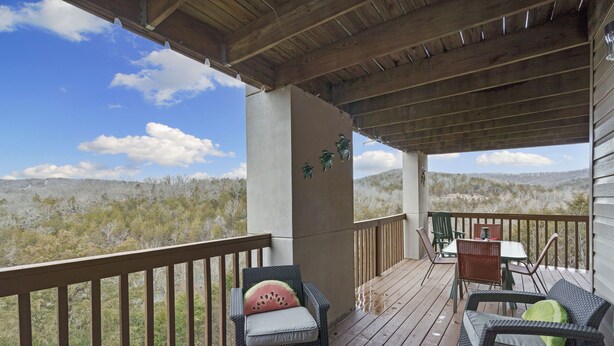 A covered outdoor deck with wicker furniture, a table, and chairs. - 3 Min to SDC. Walkin 2BR,2 Bath. condo, beautiful view of TRL and the Ozark Mtns (Branson)