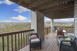 Um deck coberto ao ar livre com móveis de vime, uma mesa e cadeiras.