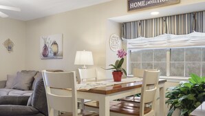 A dining area with a wooden table and white chairs, a potted plant, and a window with striped curtains. - 3 Min to SDC. Walkin 2BR,2 Bath. condo, beautiful view of TRL and the Ozark Mtns (Branson)