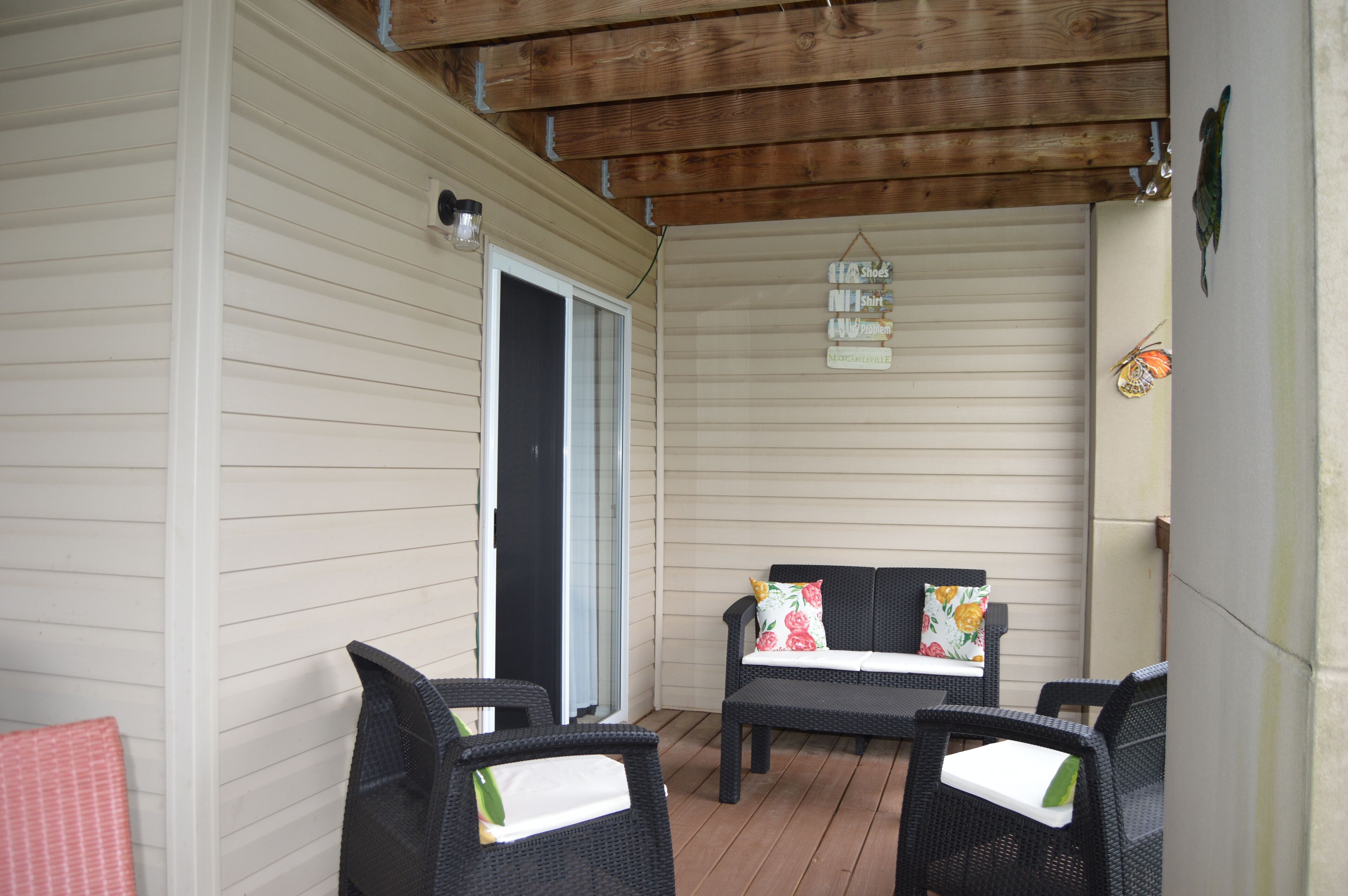 A covered patio with wicker furniture, a sliding glass door, and a hanging sign.