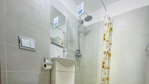 Um banheiro com vaso sanitário, pia e chuveiro.