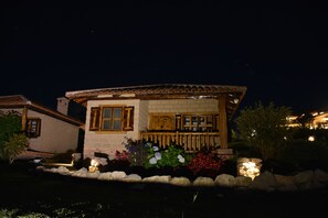 A house with a tiled roof, a stone facade, and a wooden porch.