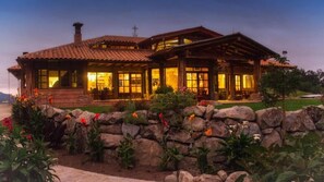 A rustic, two-story house with a stone foundation and a tiled roof.