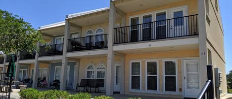 A multi-story hotel with balconies, outdoor seating, and a well-maintained garden area.