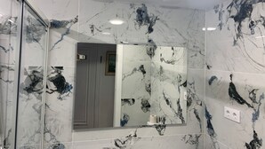 A bathroom with marble tiles and a mirror. - APARTMENT ON THE SEA IN SALOU (Salou)