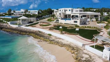 Ein Küstenresort mit mehreren weißen Gebäuden, einem Schwimmbad und einem gepflegten Garten.