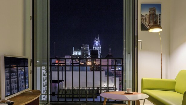 Un soggiorno moderno con vista sulla città illuminata di notte, che include una torre dell'orologio.