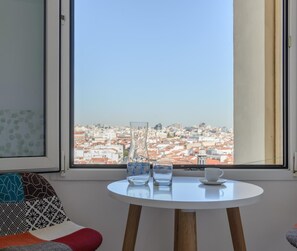 Una habitación con una mesa redonda, dos sillas y vistas a un paisaje urbano a través de amplios ventanales.