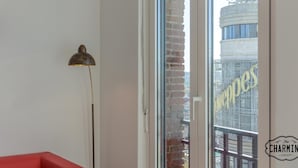 Une pièce avec une grande fenêtre, un canapé rouge et un lampadaire.