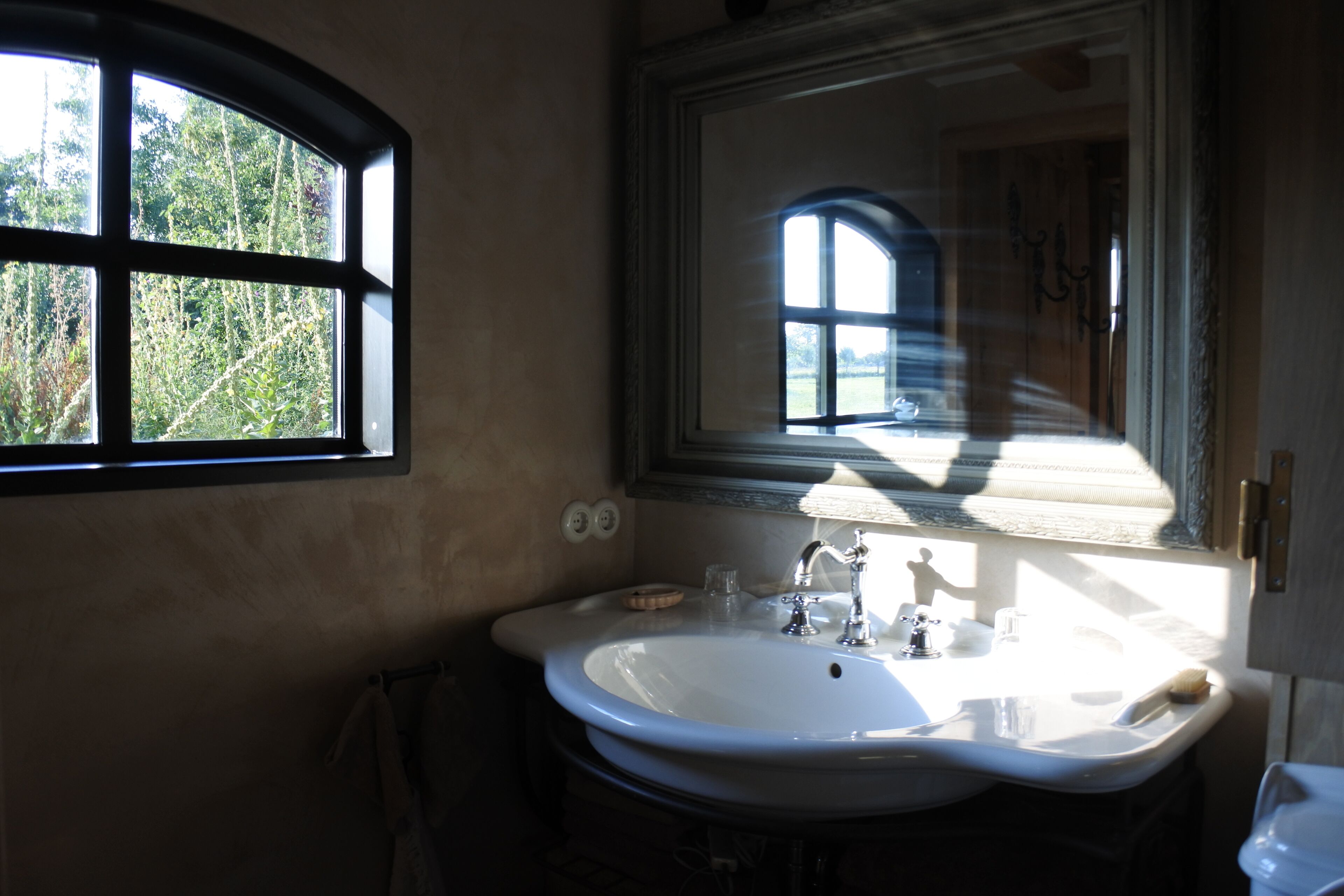 A bathroom with a large window, a sink, and a mirror.