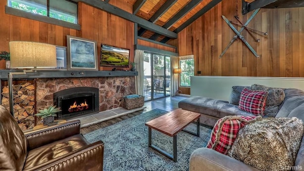 A cozy living room with a stone fireplace, leather sofas, and a large window overlooking a scenic view. - Lakeland 40 Beachfront 1BR + Loft 1BA (South Lake Tahoe)