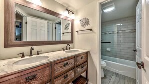 Une salle de bain avec deux lavabos, un grand miroir et une baignoire.