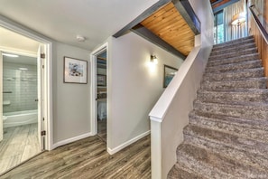 Eine Treppe mit Holzverkleidung und einer weißen Handläufe, die zu einem Raum führt, der eine weiße Tür und ein gerahmtes Bild an der Wand hat.