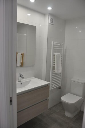 A modern bathroom with a white sink, mirror, and toilet. - Apartamento La Estambrera (Logroño)