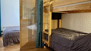 A room with two bunk beds, wooden flooring, and a window with blinds. - Le Portail 27 - Cosy 2-room apartment ski-in ski-out (LES AVANCHERS VALMOREL)