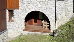 A stone building with a wooden deck and a table with chairs. - Le Portail 27 - Cosy 2-room apartment ski-in ski-out (LES AVANCHERS VALMOREL)