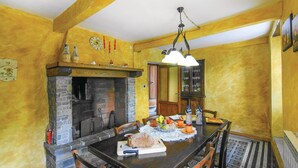 Ein Essbereich mit Kamin aus Stein, Holzbalken und einer Chandelüster.