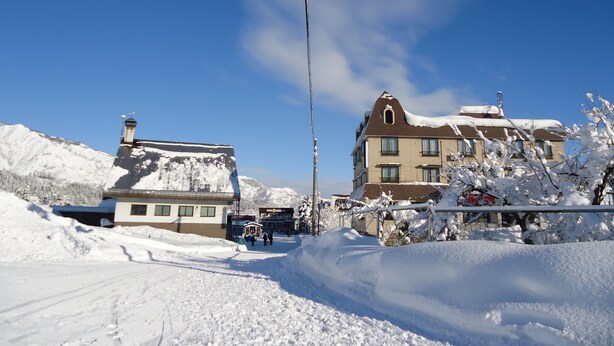 A hotel with a snow-covered roof and a clear blue sky. - New Fukudaya (Minamiuonuma)