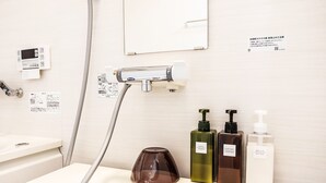 Ein Badezimmer mit Spiegel, Handtuchhalter, Duschkopf und Toilettenartikeln, darunter Shampoo, Spülung und Duschseife.