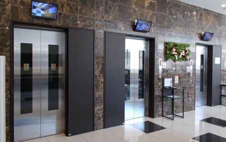 A modern lobby with marble walls, elevators, and a reception area.