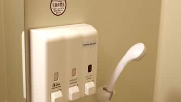 A wall-mounted dispenser with buttons for face and body wash, conditioner, and shampoo.