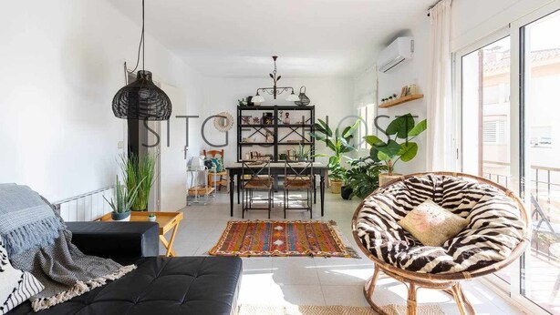 A modern living room with a black sofa, a zebra-patterned chair, a dining area with a chandelier, and large windows. - Stylish home with patio 5 mins to beach (Sitges)