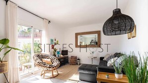 A modern living room with a zebra-patterned chair, a black sofa, and a large black pendant light. - Stylish home with patio 5 mins to beach (Sitges)