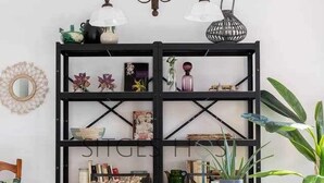 A dining area with a black metal bookshelf, two wicker chairs, a table, and a chandelier. - Stylish home with patio 5 mins to beach (Sitges)