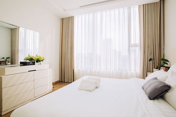 Una habitación de hotel con cama, cómoda y un gran ventanal con cortinas.