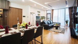 Ein modernes Wohnzimmer mit einer Couch, einem Esstisch für vier Personen und einer Küchenzeile im Hintergrund.