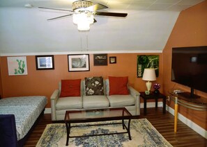 A living room with a sofa, a coffee table, a TV, and a ceiling fan.