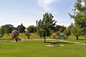 A playground with various play structures, a picnic table, and a well-maintained grassy area. - The City Pads: conveniently located, with everything just a short walk away. (Grand Forks)