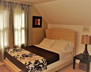A bedroom with a bed, a nightstand, a lamp, and a framed picture on the wall.