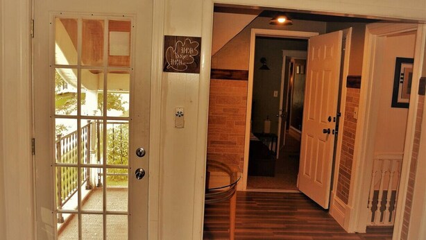 A hallway with a wooden floor, a glass door leading to an outdoor area, and a brick wall. - The City Pads: conveniently located, with everything just a short walk away. (Grand Forks)
