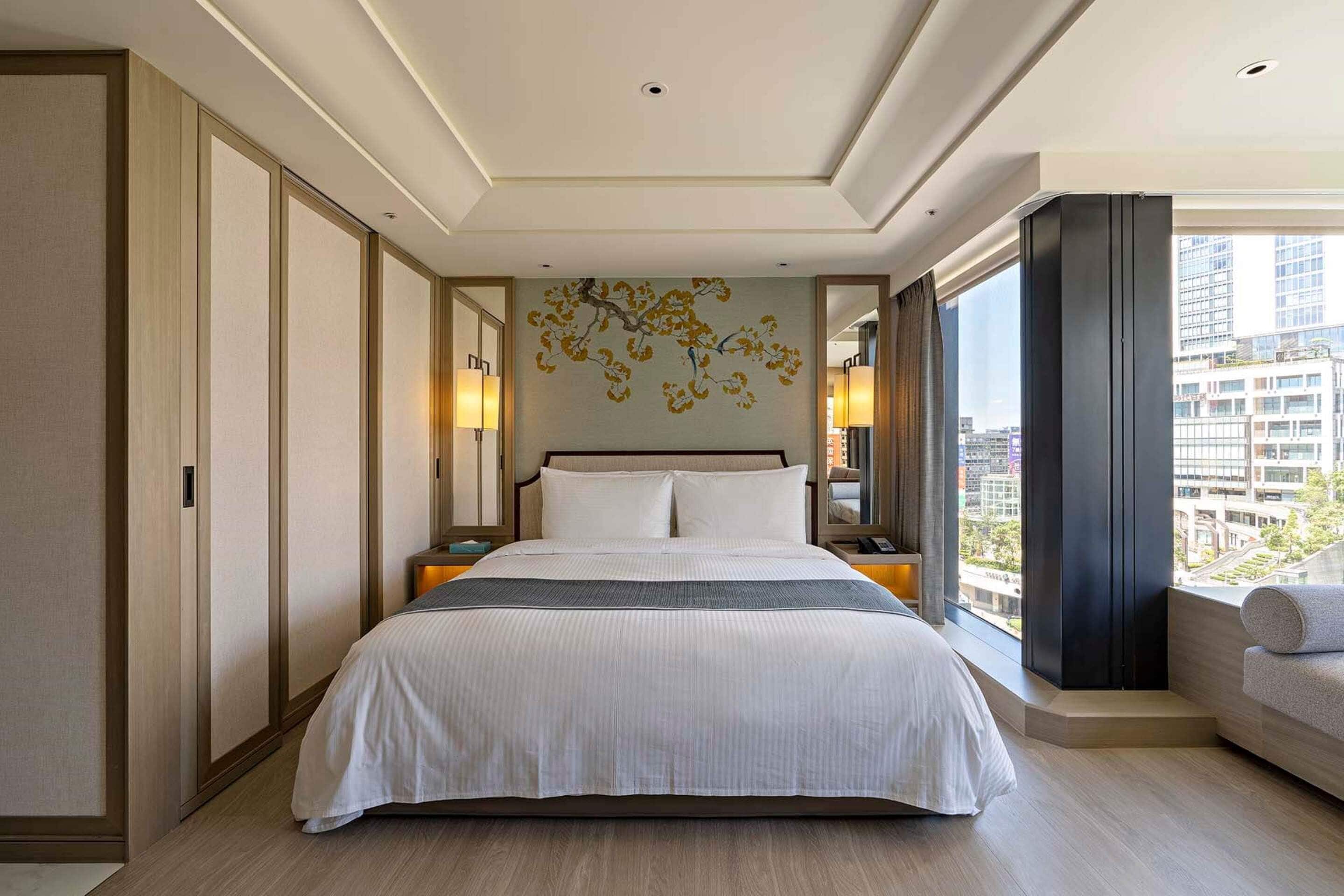Habitación de hotel moderna con una cama grande, vistas a la ciudad y un adorno en la pared.