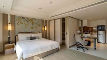 Una habitación de hotel moderna con una cama grande, un escritorio y una kitchenette.