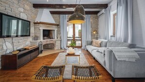 Un salon avec une cheminée en pierre, un canapé, un téléviseur et une table basse en bois.