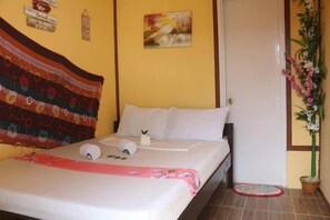 A bed with white linens, a colorful blanket, and a small potted plant beside it. - El Nido Hostel Sun Valley (El Nido)