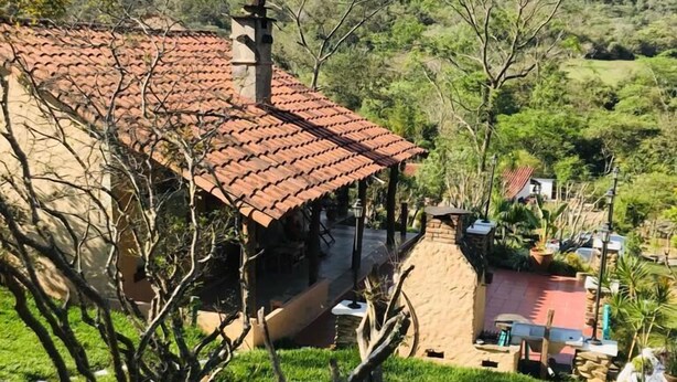 A building with a red-tiled roof, surrounded by a well-maintained garden with various plants and a stone pathway. - Cabañas Sebastian (Cuevas)