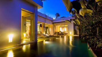 Una casa moderna con piscina, puertas de cristal y un interior bien iluminado.